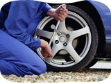 Person checking tyres and tightening wheel bolt