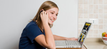 Girl on phone looking at laptop 