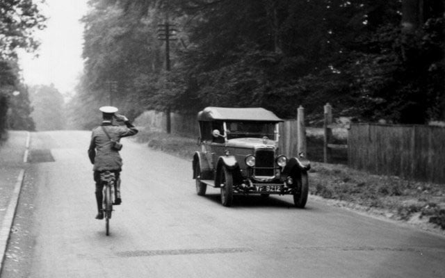 An early AA patrol on a bicycle salutes a passing car