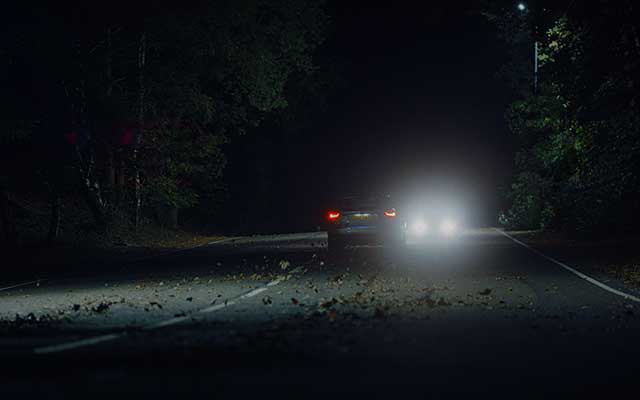 A drowsy driver veers across the road into the path of  oncoming headlights