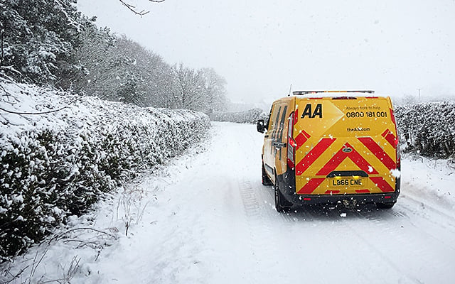 An AA patrol van driving in snow