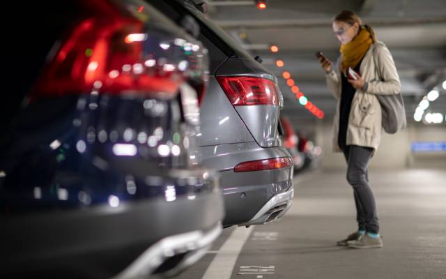 woman approaching a large SUV that overhangs a parking space