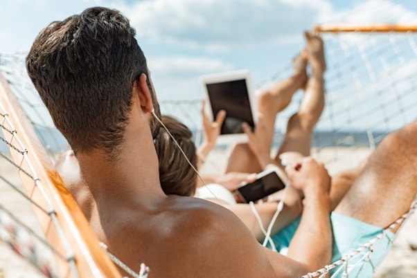 couple on a beach holding mobile devices