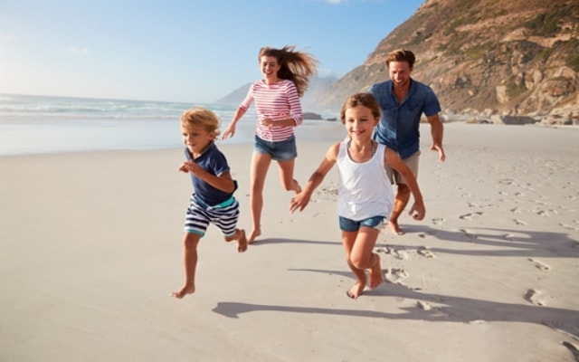 Kids on holiday running across a sunny beach
