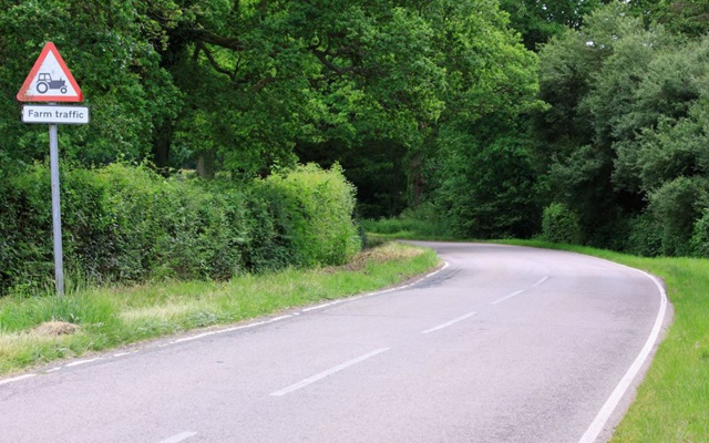 A country road with a farm traffic sign