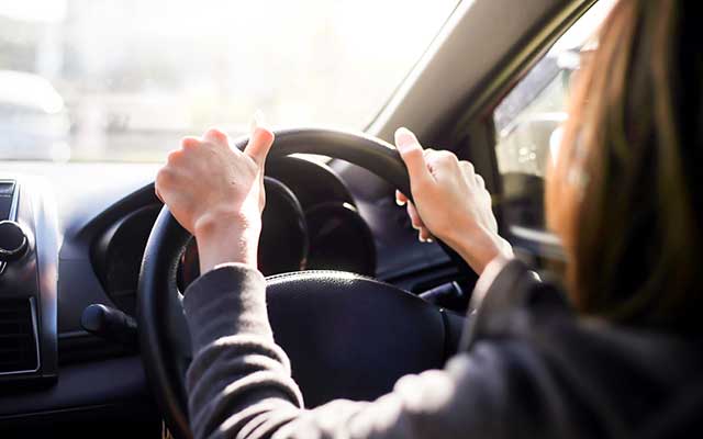 Woman in car with hands on steering wheel 