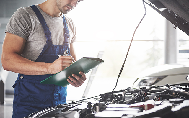 Car mechanic looking under the bonnet of a car