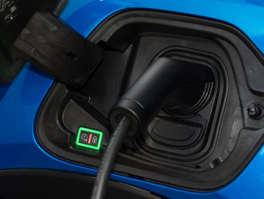 An image of a blue Peugeot e 208 charge port plugged in