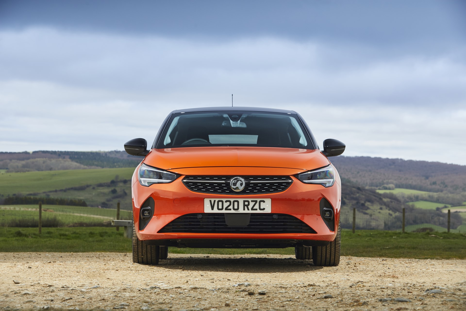 A Vauxhall Corsa E in Power Orange paint colour photographed from head on in the countryside