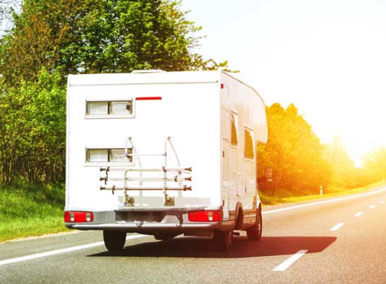 A large white motorhome driving on the left-hand lane of a rural dual carriageway