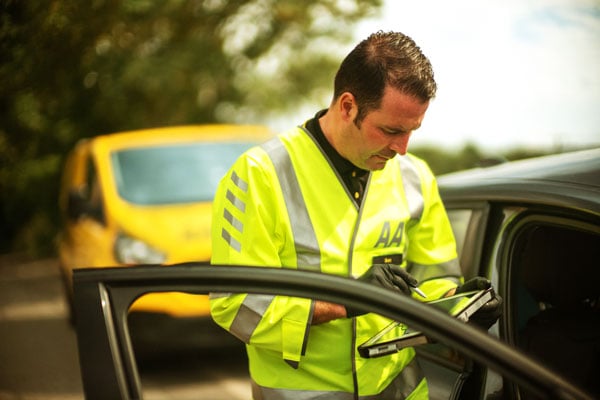 AA patrol checking device An AA patrol checks his device while attending a breakdown