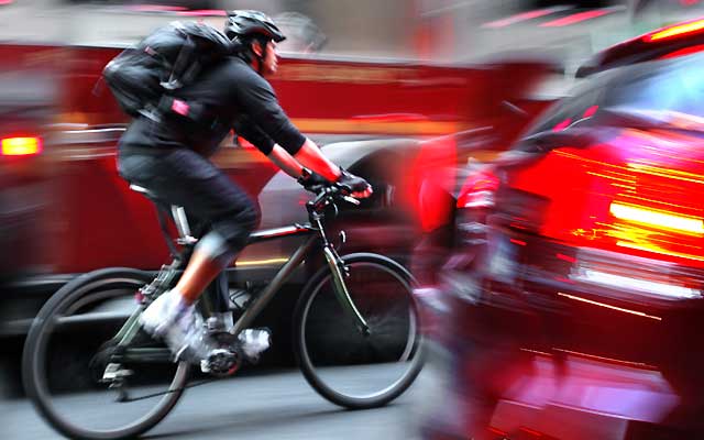 Cyclist passing cars on black bike